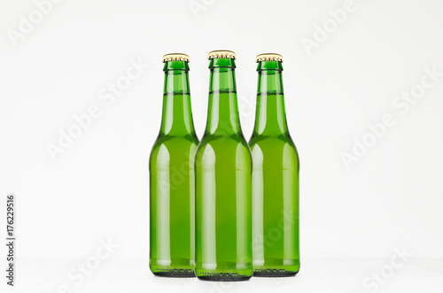 Group green longneck beer bottles 330ml, mock up. Template for advertising, design, branding identity on white wood table.