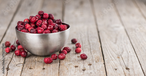 Some fresh Dried Cranberries on wooden background (selective focus; close-up shot)