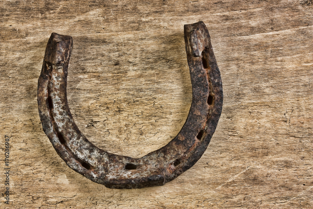 old rusty horseshoe on a wood background old rusty horseshoe on a wood background