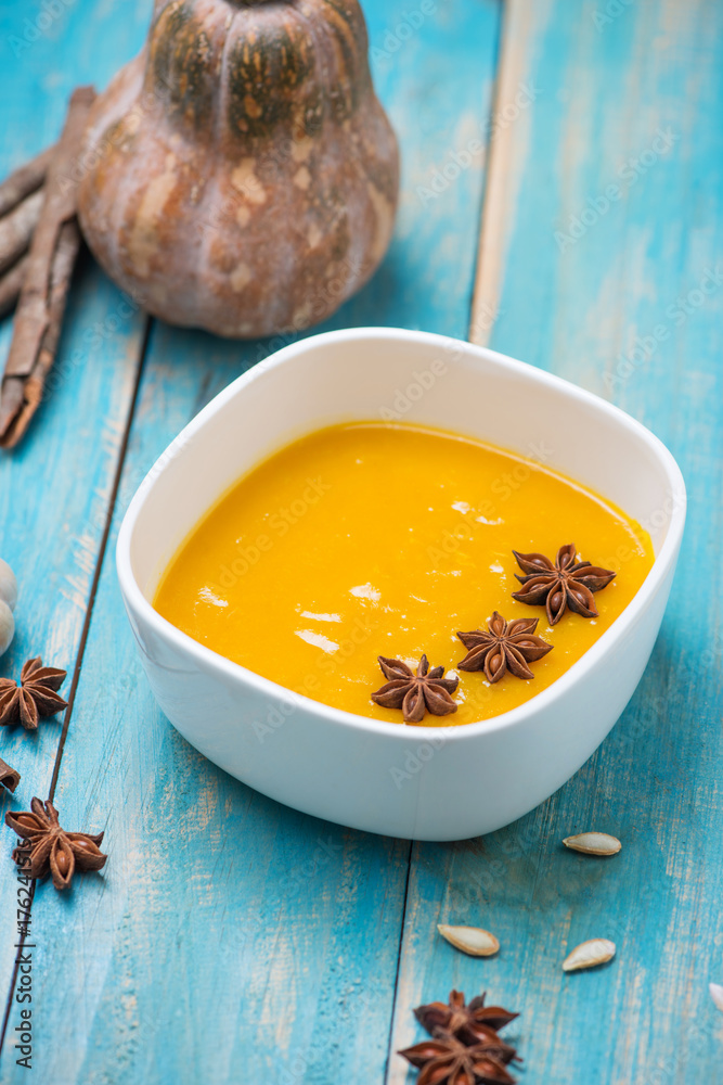 Pumpkin and carrot soup with cream and parsley on blue wooden background. Pumpkin and carrot soup with cream and parsley on blue wooden background.