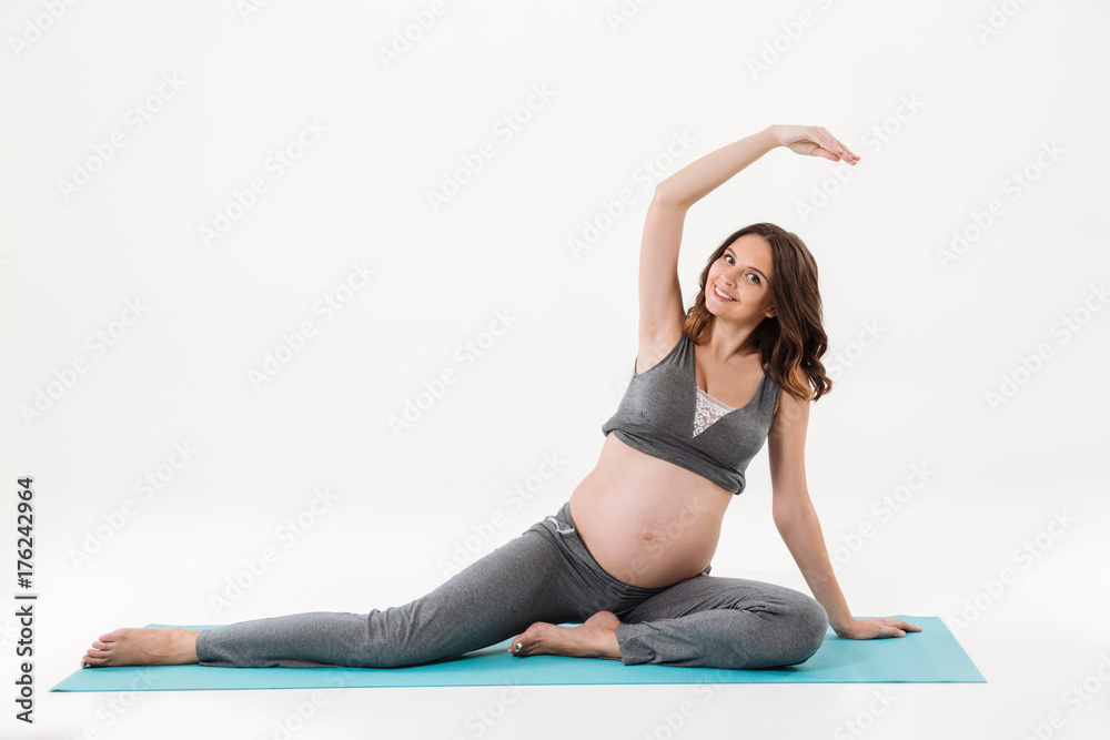 Obraz premium Happy pregnant woman doing fitness exercise on fitness mat