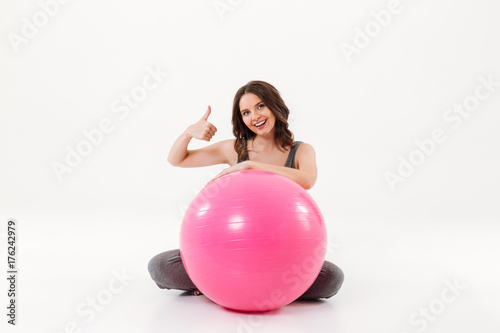 Happy pregnant woman sitting on the floor with fitball