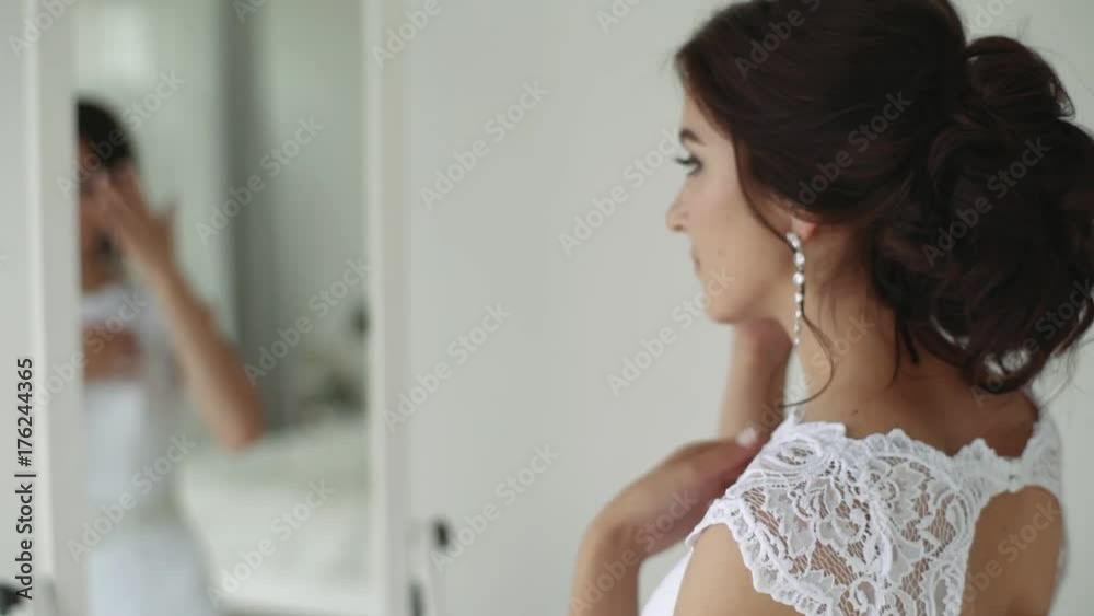 Girl wears earrings in front of a mirror. Girl wears earrings in front of a mirror.