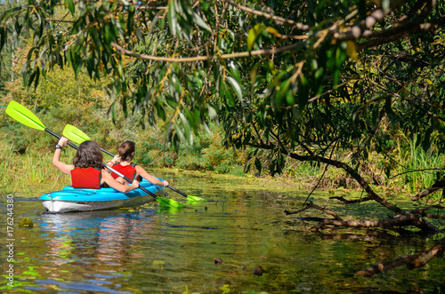 Family kayaking, mother and child paddling in kayak on river canoe tour, active autumn weekend and vacation, sport and fitness concept
