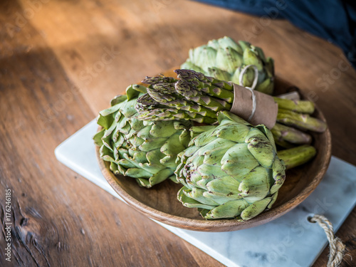 Organic green vegetables food in wood bowl. Asparagus and artichoke on wooden background.
