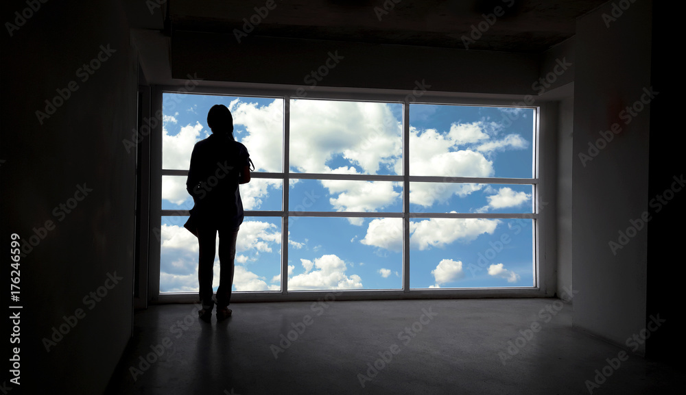 Back or rare view of women silhouette beside the big window and sky with cloud background,freedom concept