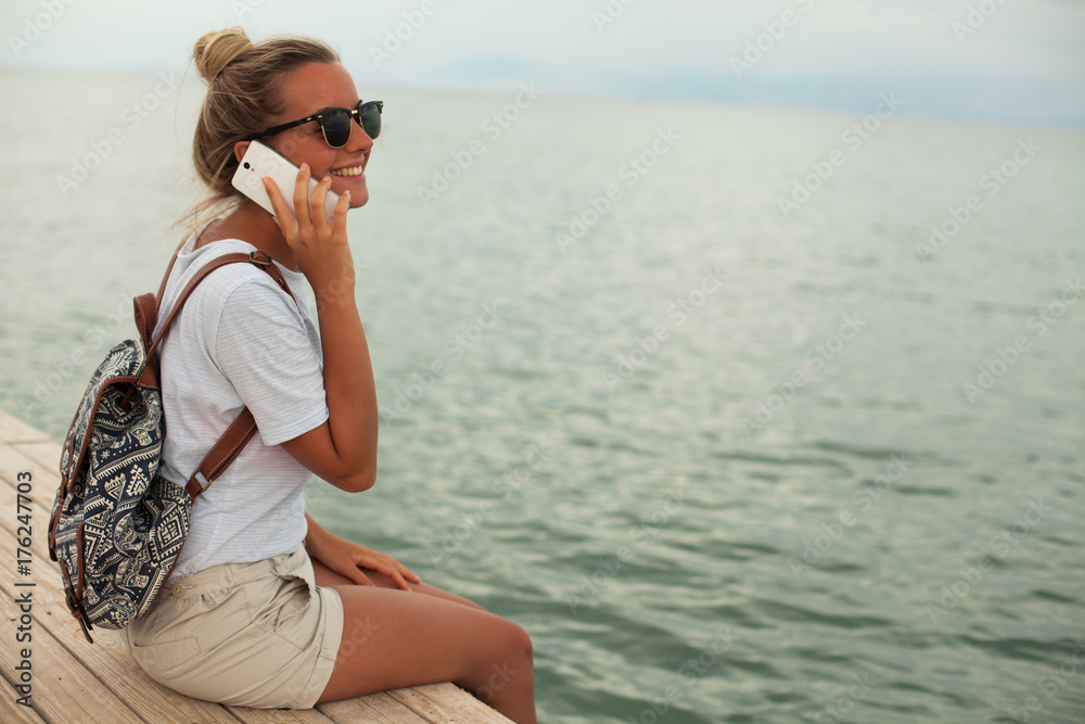 Happy young woman talking on phone at seaside