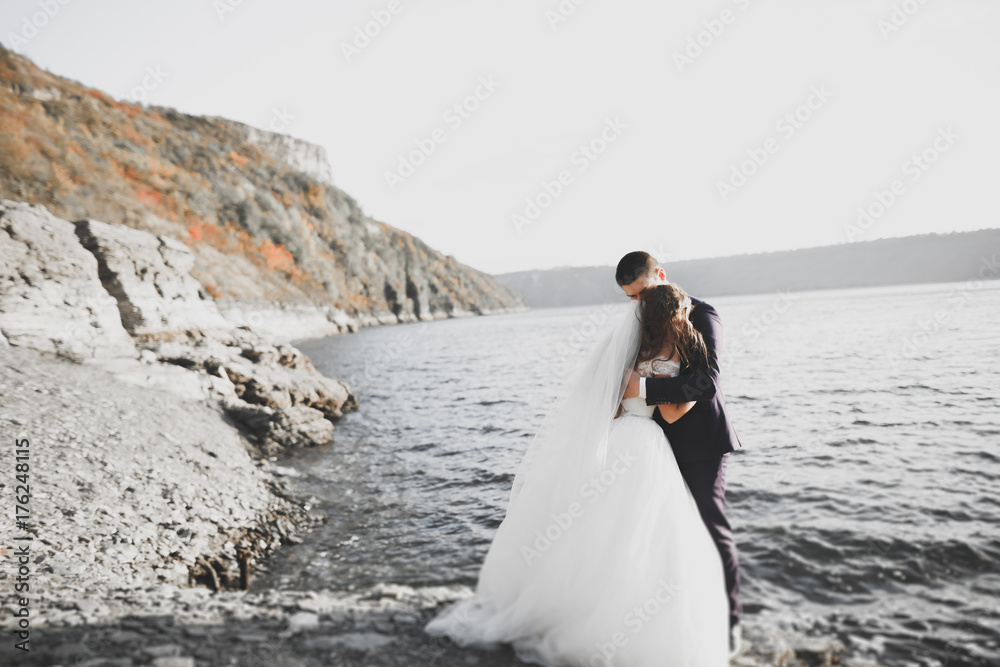 Happy and romantic scene of just married young wedding couple posing on beautiful beach Happy and romantic scene of just married young wedding couple posing on beautiful beach