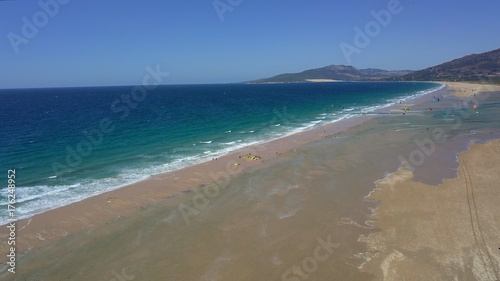 Aerial shot of wonderful view of ocean turquoise water washing sands of beach in tropics making white foam in bright light.