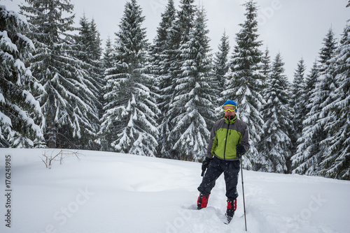 Traveler man, in a goggles, stands in a deep snow
