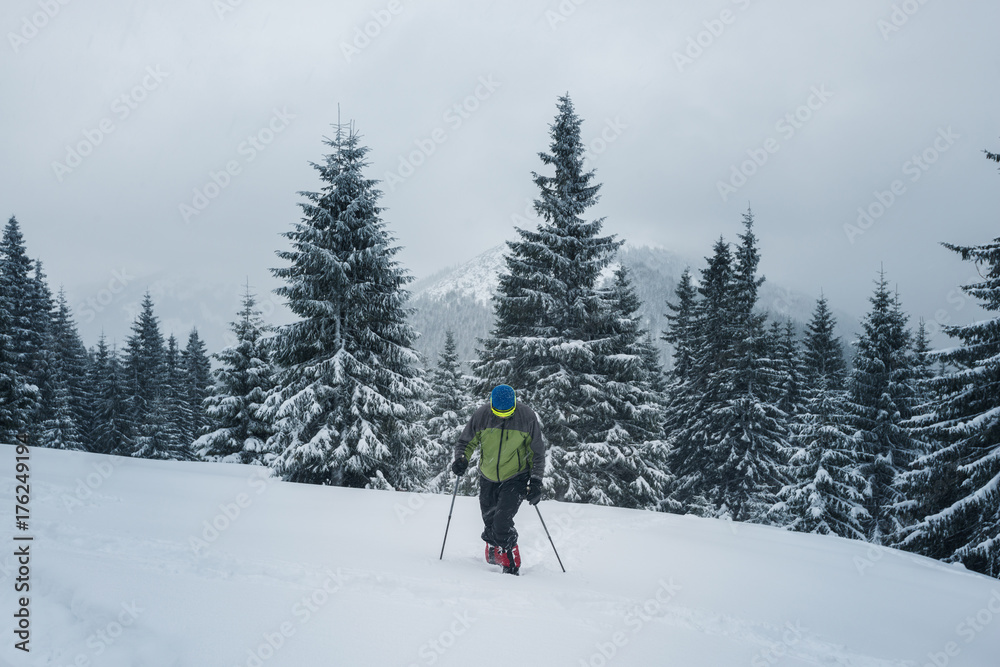 Adventurer, in snowshoes, climbs up the slope