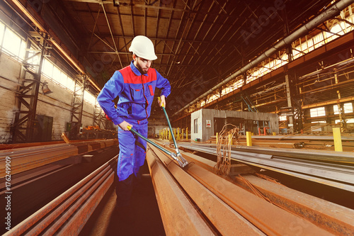 Industrial worker cuts steel wire with large pasatils cutters on the background of the plant