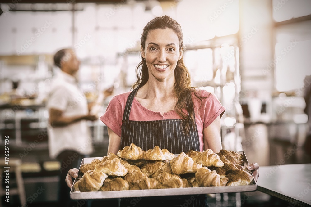  Female baker showing tray of fresh croissants