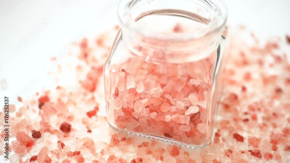 Pink Himalayan salt in a jar rotating on a white background. Big crystals in glass pot for kitchen and beauty Pink Himalayan salt in a jar rotating on a white background. Big crystals in glass pot for kitchen and beauty