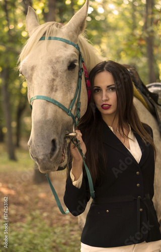 Young brunette beauty girl having fun with horse in the park