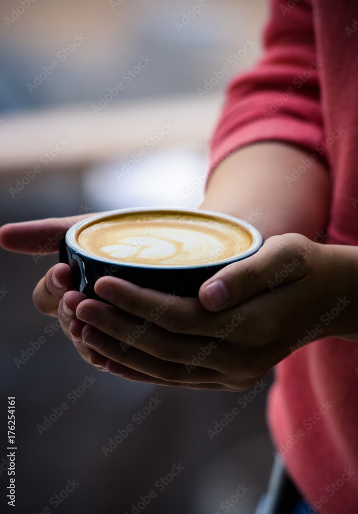 Perfectly brewed cappuccino and fresh roasted Arabica beans in the cozy atmosphere of a coffee shop. Professional barista or a client is going to taste a cup of coffee. Perfectly brewed cappuccino and fresh roasted Arabica beans in the cozy atmosphere of a coffee shop. Professional barista or a client is going to taste a cup of coffee.