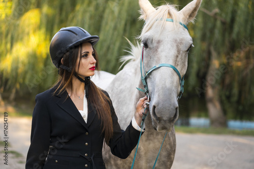 Young brunette beauty girl leading horse in the park