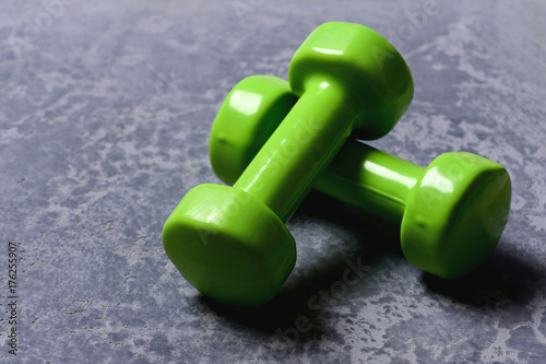 Dumbbells made of bright green plastic on grey texture background