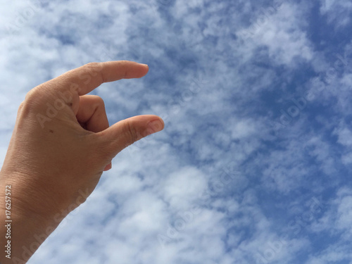 female hand holding virtual card or blank paper against blue sky