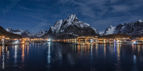 Village on the Lofoten Islands at night, in the foreground the sea in the background the mountains