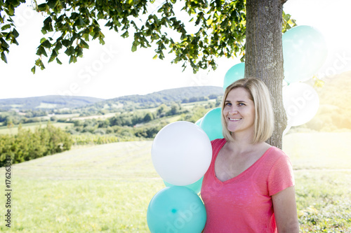 Happy Woman with balloons standing on the meadow