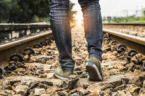 Woman wear jeans and sneaker shoes walk on the train railway,