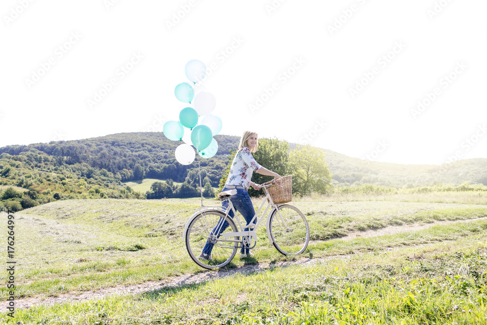 Happy Woman driving by bike with balloons