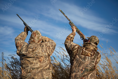 Obraz na plátne Duck hunters aiming into sky with guns