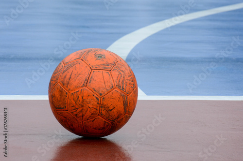old and damaged orange ball at futsal court photo