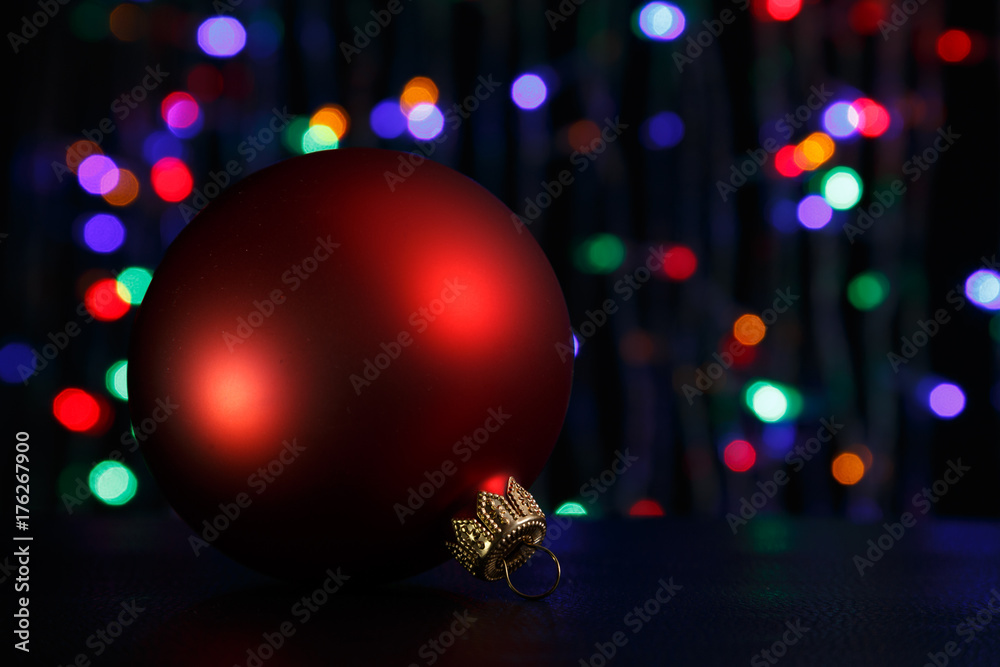 Obraz premium Red christmas ball on dark. Out of focus christmas lights background.