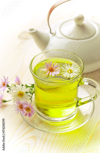 Green tea in a cup on a background of dry leaves of floral tea in a composition with accessories on a white background