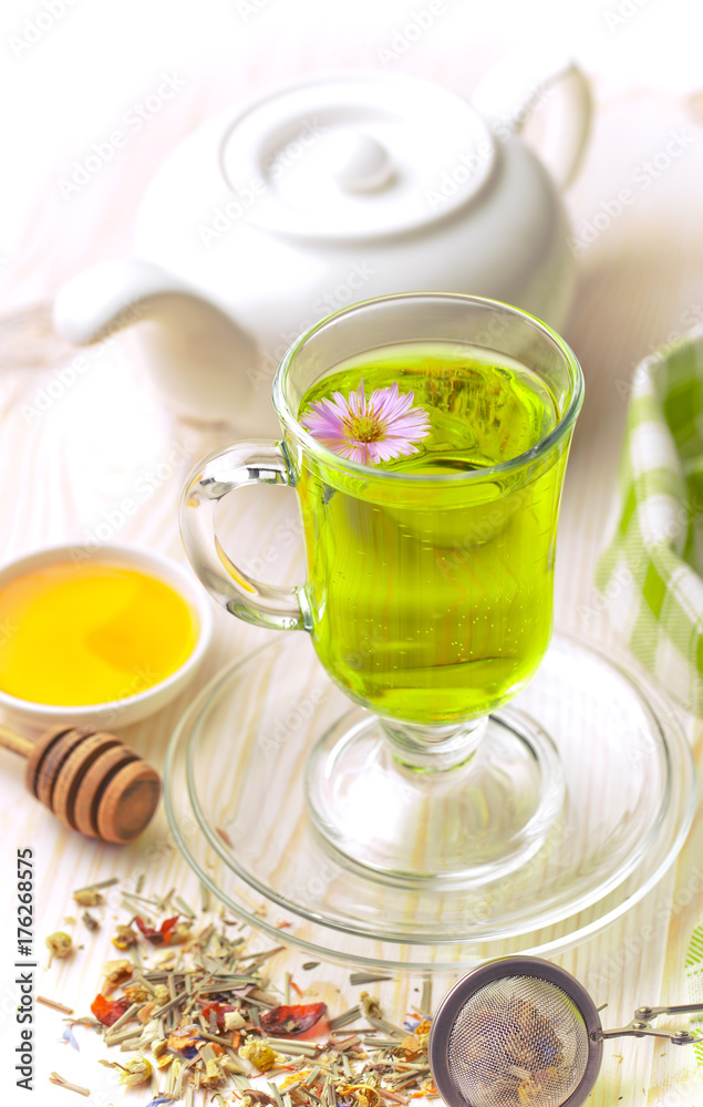 Green tea in a cup on a background of dry leaves of floral tea in a composition with accessories on a white background Green tea in a cup on a background of dry leaves of floral tea in a composition with accessories on a white background