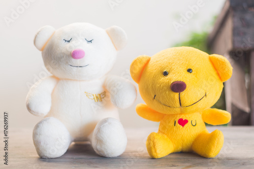 white and yellow teddy bear sitting on wood floor with blur background and vintage tone © dadatop