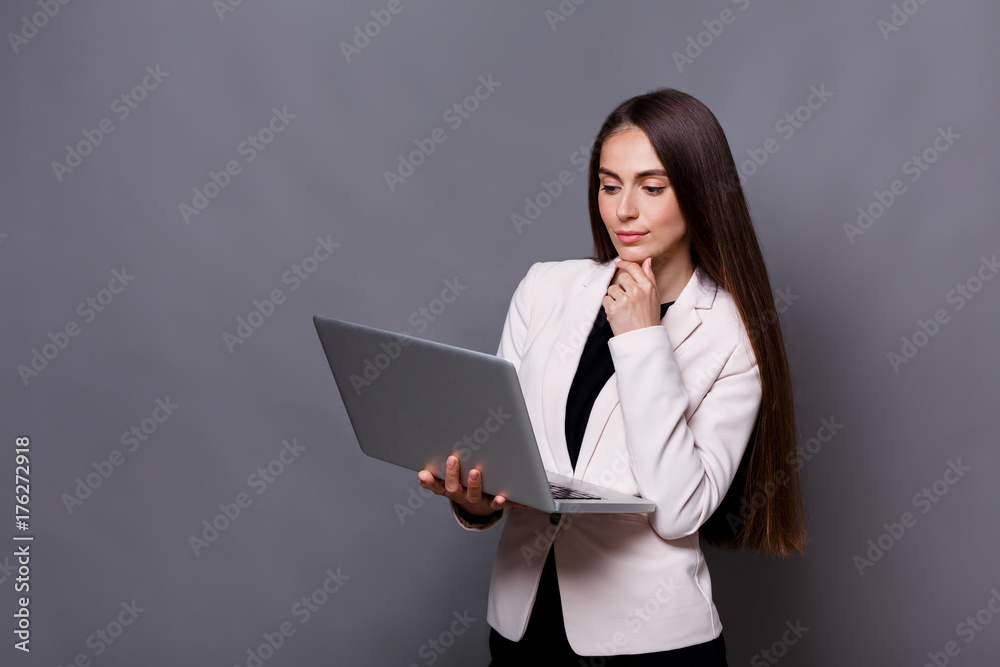 Pensive business woman with laptop on gray background Pensive business woman with laptop on gray background