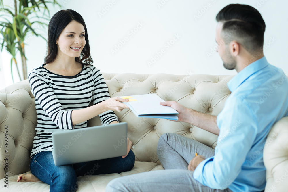 Fototapeta premium Friendly millennial people handing over notebook