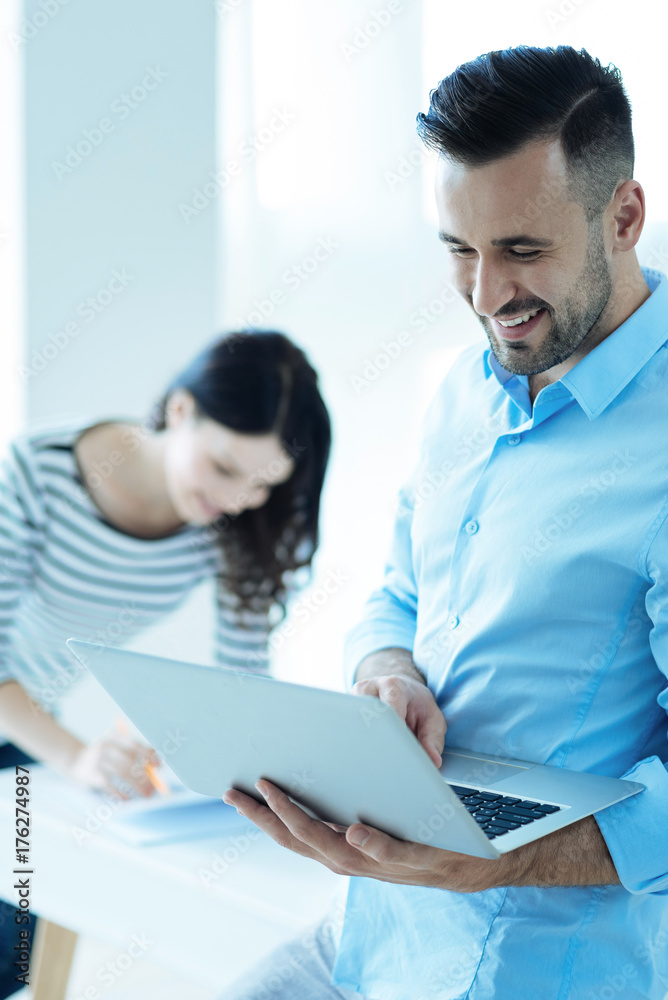 Joyful successful man working on laptop at office