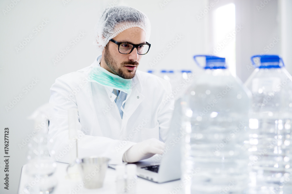 Young handsome scientist with glasses working on laptop in the laboratory. Young handsome scientist with glasses working on laptop in the laboratory.