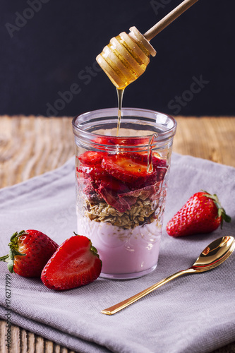 Yogurt with musli and strawberries poured with honey