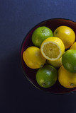 Limes and lemons in a dark bowl on a black table
