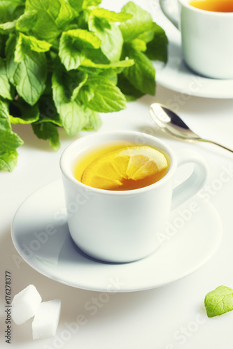 Fresh black tea with lemon and mint on a white table