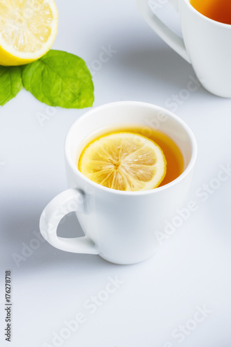 A cup of black tea with lemon on a white table