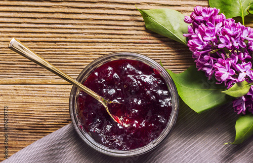 Marmelade jar and lilac on a wooden table