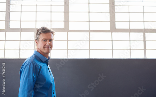 Confident mature businessman standing alone in a modern office