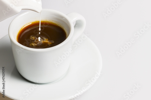 Pouring milk to fresh black coffee