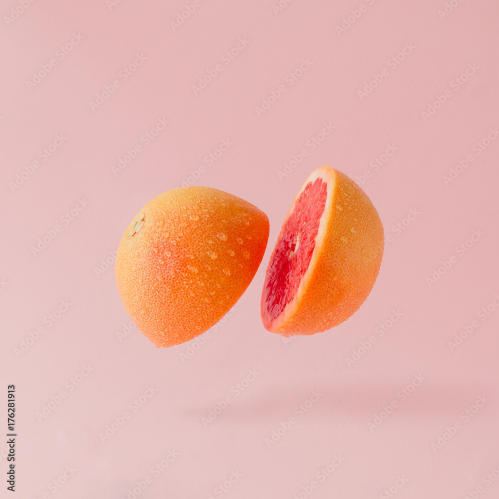 Fototapeta Grejpfruty w plasterkach na pastelowym różowym tle. Minimalna koncepcja owoców.