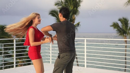 Young beautiful happy couple. Ukrainian girl and Mexican man. Look at each other, hugging, kissing, ...dancing on the roof in the caribbean resort