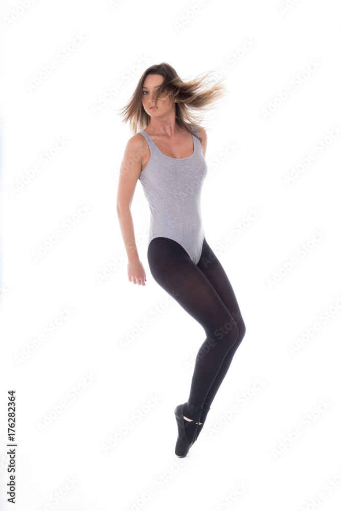 young beautiful woman dancer with long black hair wearing gray vest and tights jumping on a light white studio background