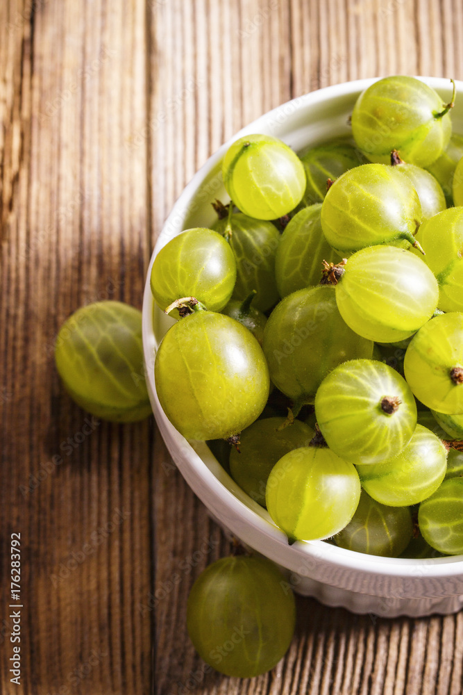 Homegrown gooseberries in a ceramic bowl on wooden table Homegrown gooseberries in a ceramic bowl on wooden table