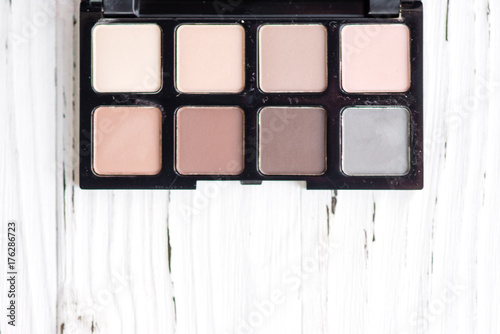 Top view of pink and brown tone make up palette on white wooden background