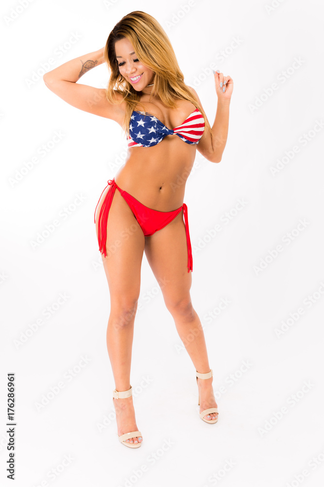 Young fit hispanic woman in American Flag patterned swimsuit posing on a white background Young fit hispanic woman in American Flag patterned swimsuit posing on a white background